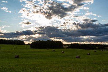 Günbatımında saman ruloları olan yeşil manzara