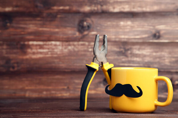 Желтая чашка с плоскогубцами на коричневом столе
