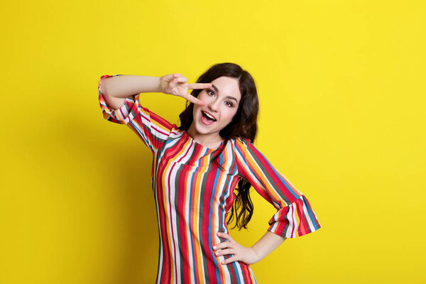 Young woman in striped dress on yellow background