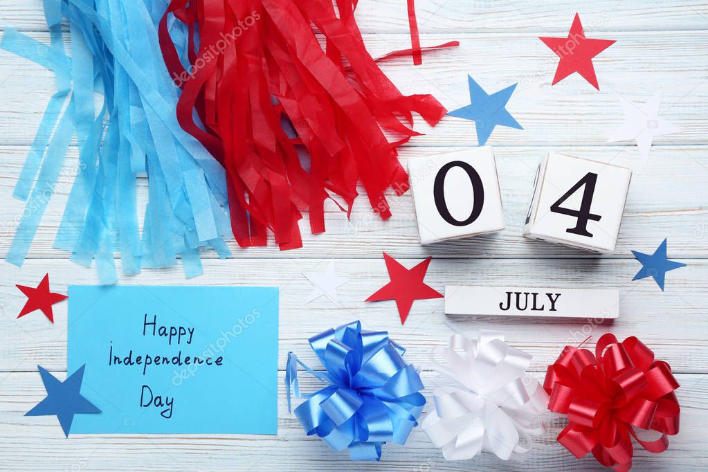 Cube calendar, pom poms and paper with inscription Happy Independence Day on wooden table