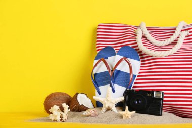 Sarı zemin üzerine deniz kabuklarını ve retro kamera Flip flop