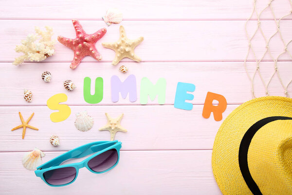 Inscription Summer with seashells and accessory on pink wooden table