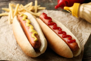 Hot dogs with mustard and ketchup on wooden table clipart