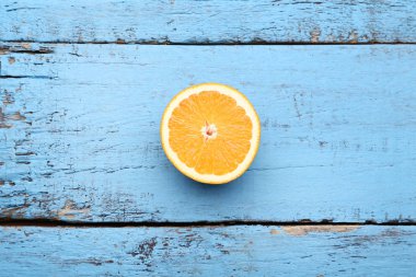 Mavi ahşap masa üzerinde turuncu meyve yarısı