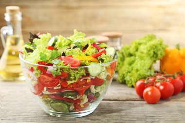 Gri ahşap masa üzerinde cam kase sebze salatası