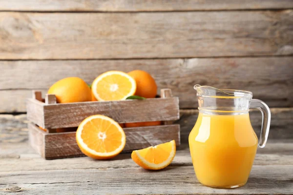 Portakal suyu gri ahşap masa üzerinde sürahi ile sandık içinde
