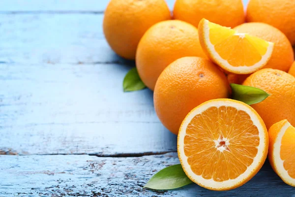 Mavi ahşap masa üzerinde yeşil yaprakları ile portakal