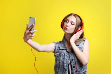 Selfie üzerinde sarı arka plan yapma kulaklık ile genç kadın