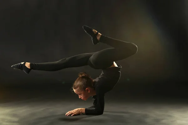 在黑色背景上的年轻女孩体操运动员 — 图库照片