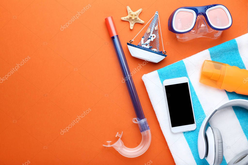 Summer accessories with smartphone and diving mask on orange background