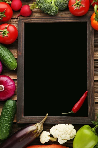 Black wooden frame with vegetables on brown table