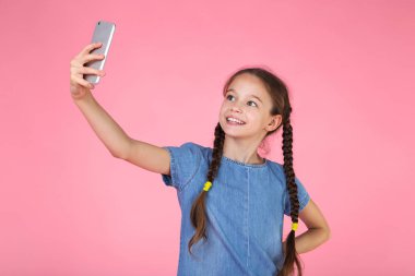 Genç kız kot elbise yapma selfie, pembe arka plan