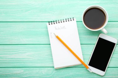 Smartphone ve ahşap masa üzerinde kahve ile not etmek içinde listelemek için