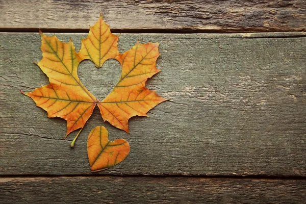 Dry maple leaf with heart on grey wooden table