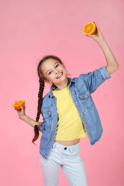 Young girl with orange fruit on pink background