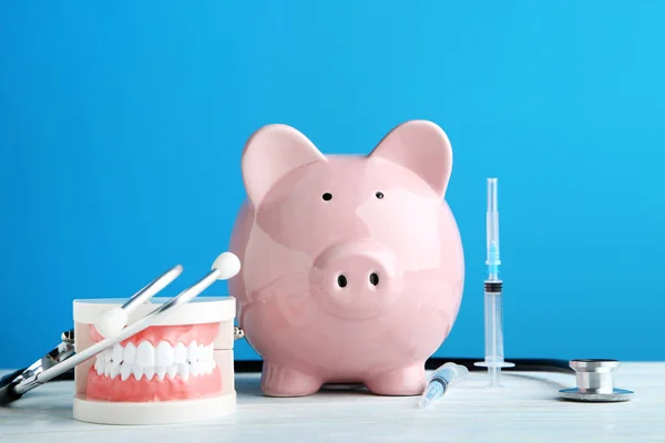 粉红色的小猪银行与听诊器 注射器和牙齿模型在蓝色背景 — 图库照片