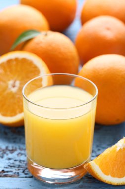 Cam suyu mavi ahşap masa üzerinde turuncu meyveler