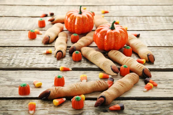 Halloween finger cookies with candies on brown wooden table
