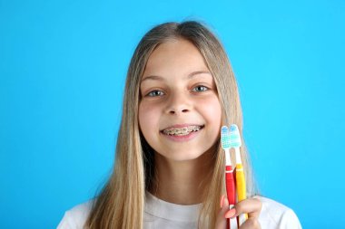 Diş diş telleri ve mavi arka plan üzerinde diş fırçası ile genç gülümseyen kız