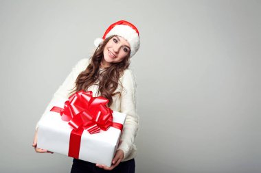 Noel Baba şapkası ile hediye kutusu gri arka plan üzerinde genç kadın