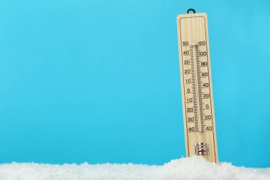 Mavi arka plan üzerinde karda ahşap termometre