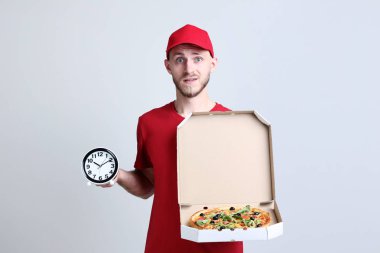 Teslimatçı karton kutu ve gri arka plan üzerinde saatin pizzayla
