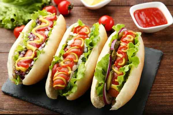 木桌上加番茄酱 芥末和蔬菜的热狗 — 图库照片
