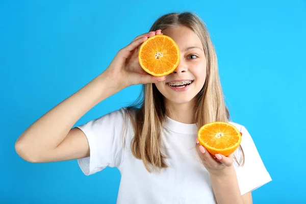 Gadis Tersenyum Muda Dengan Buah Oranye Latar Belakang Biru — Stok Foto