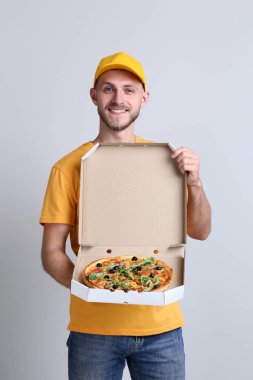 Gri arka plan üzerine karton kutu içinde pizza teslimi adam