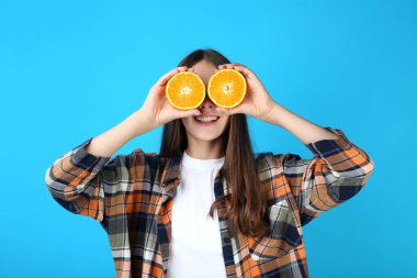 Mavi arka plan üzerinde turuncu meyve ile genç kız