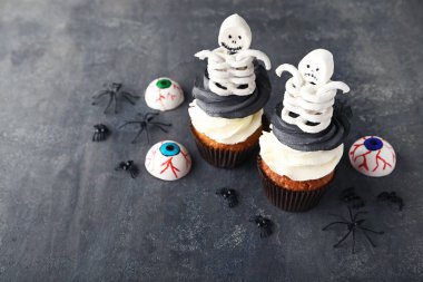 Gri ahşap masa üzerinde iskeletler ile Halloween cupcakes