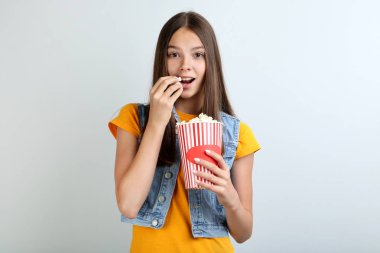 Kova gri arka plan üzerinde patlamış mısır ile tutan genç kız