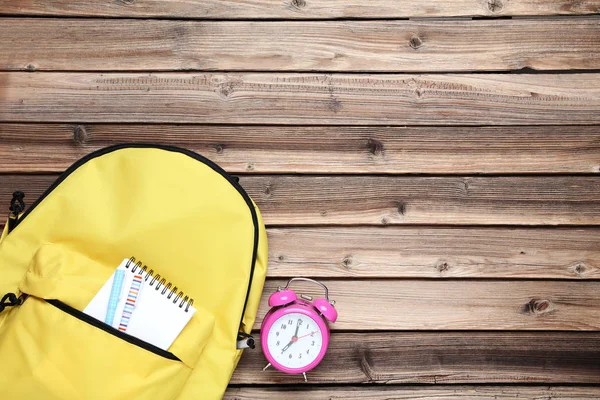 Gelber Rucksack Mit Notizbuch Und Wecker Auf Braunem Holztisch — Stockfoto