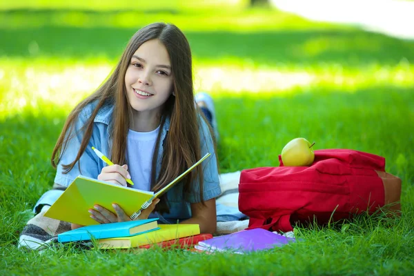ノートや書籍の横になっているかわいい女の子公園で — ストック写真