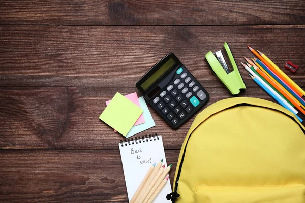 Gelber Rucksack Mit Schulbedarf Auf Braunem Holztisch — Stockfoto