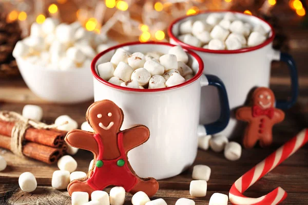 Cappuccino with marshmallow in mugs and gingerbread cookies on wooden table