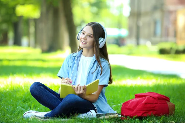 Leuk Meisje Zittend Met Boek Koptelefoons Het Park — Stockfoto