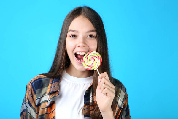 Молодая девушка с леденцом на синем фоне
