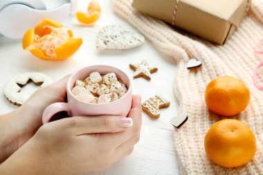 Kahve Marshmallow, mandalina ve gingerbread çerezleri tutan eller