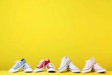 Sarı arka plan üzerinde farklı renkli spor ayakkabı