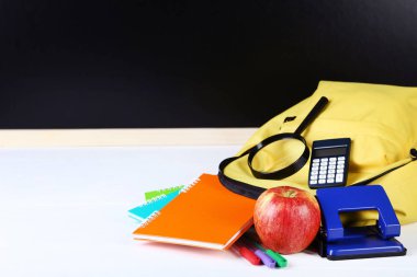 Siyah zemin üzerine sarı sırt çantası ile okul malzemeleri