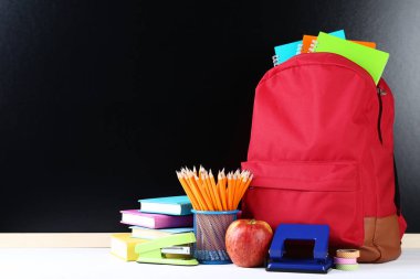 Siyah zemin üzerine kırmızı sırt çantası ile okul malzemeleri