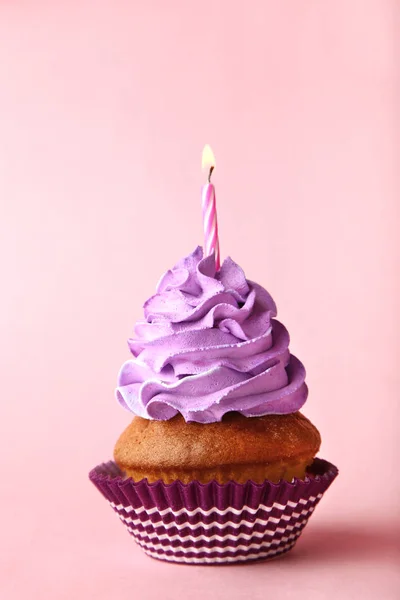 ピンクの背景にキャンドルのあるおいしいカップケーキ — ストック写真