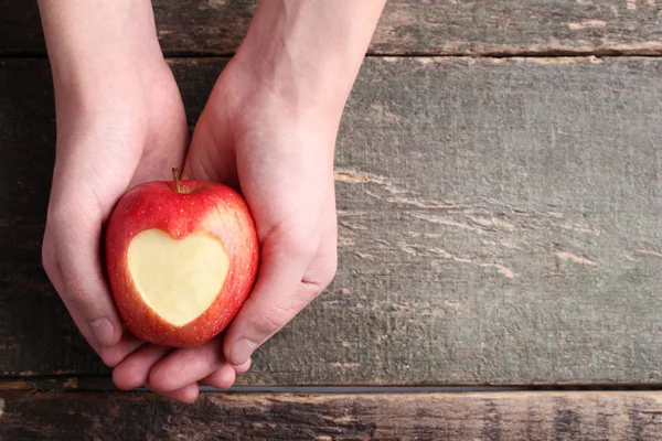 Female Hands Holding Red Apple Cutout Heart Shape Wooden Background — Stock Photo, Image