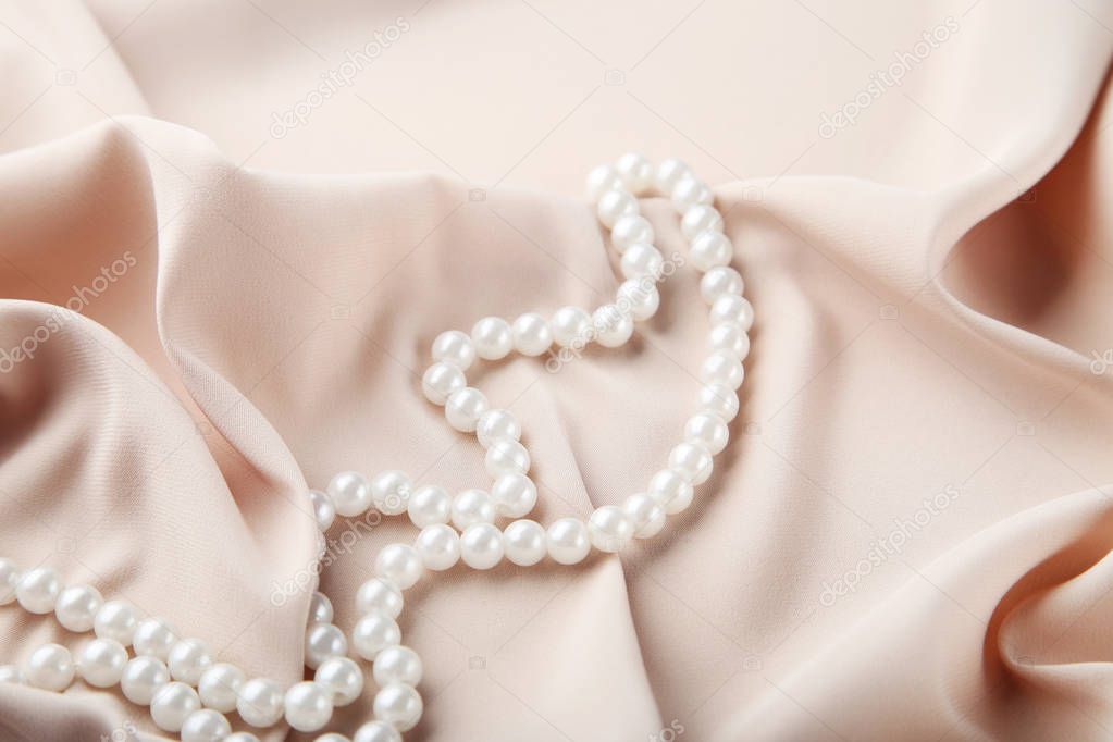 Pearl necklace on beige satin fabric