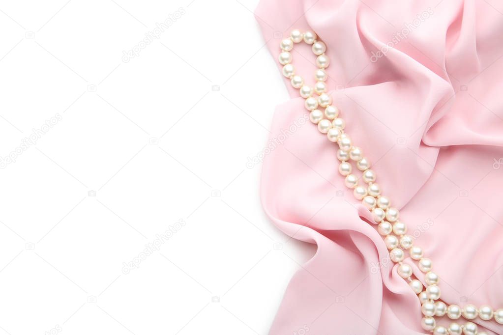 Pearl necklace with pink satin fabric on white background