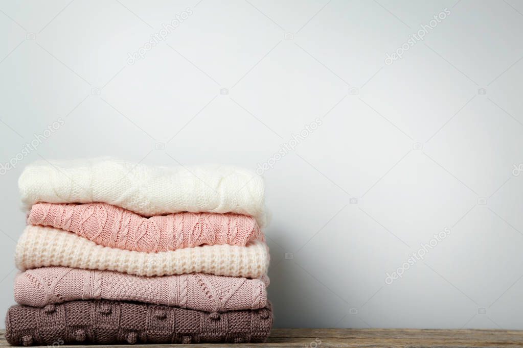 Stack of knitted sweaters on grey background