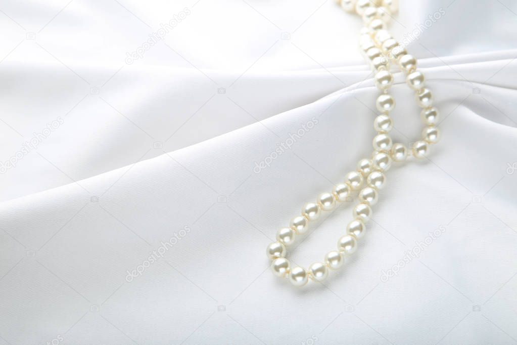 Pearl necklace on white satin fabric