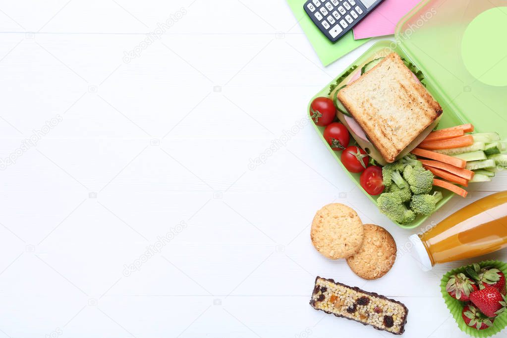 School lunch box with sandwich and vegetables on wooden table