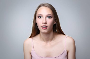 Kameraya gri arka plan üzerinde seyir sürpriz çekici kadın portresi
